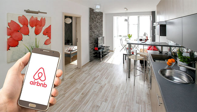 holiday accommodation with a hand holding a mobile phone with Airbnb app